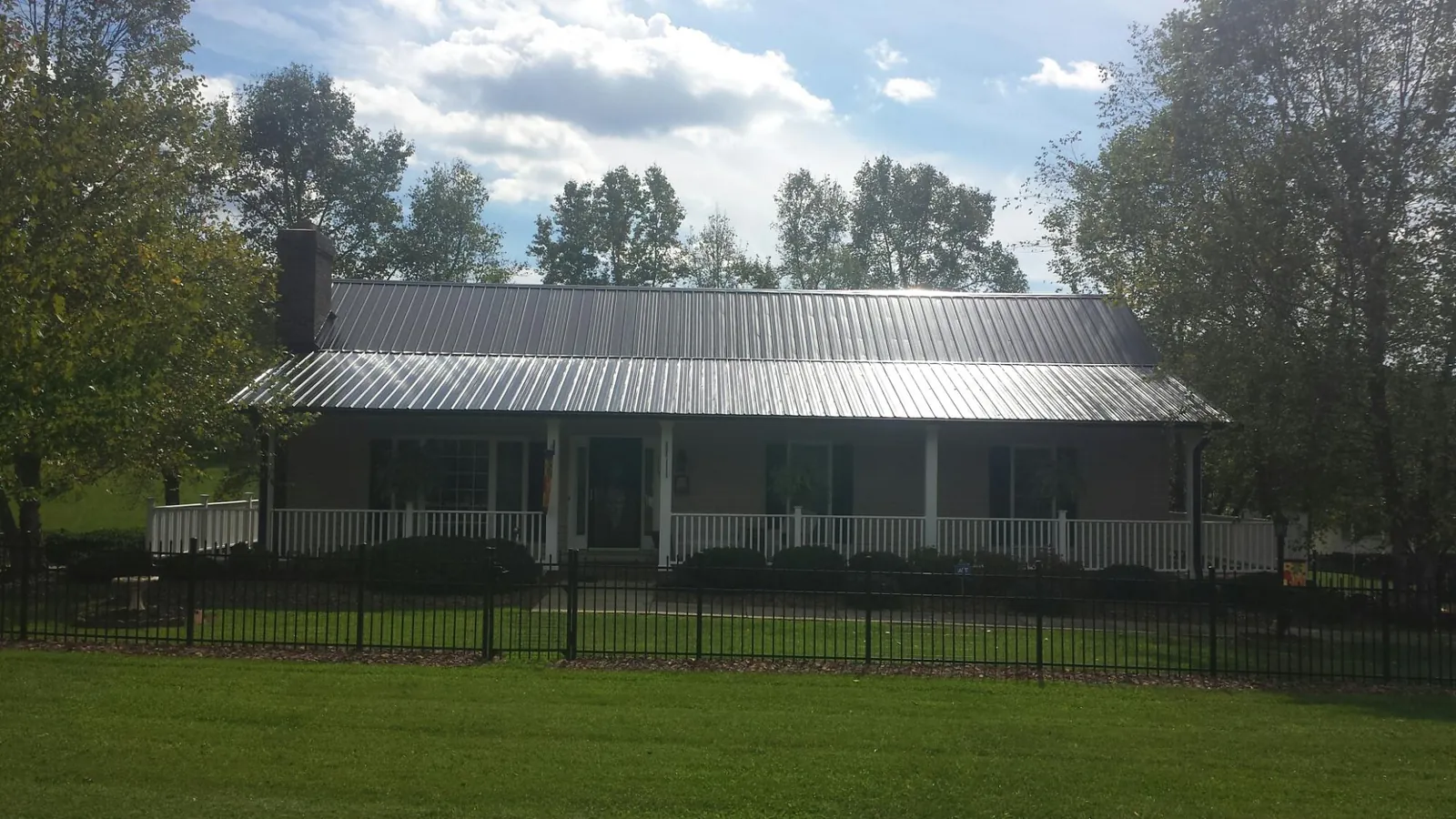 Gray metal roof on a brick ranch with a full width front porch — Gutter Guard Installation work by our crew in Plainview