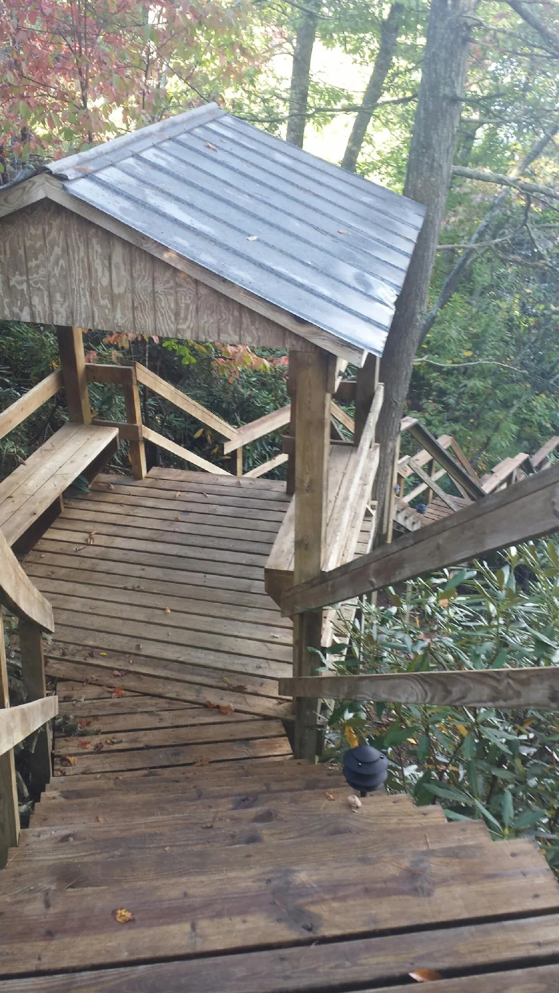 Metal roofed shelter over wooden steps on a wooded walkway — Skylight Repair & Installation work by our crew in Plainview