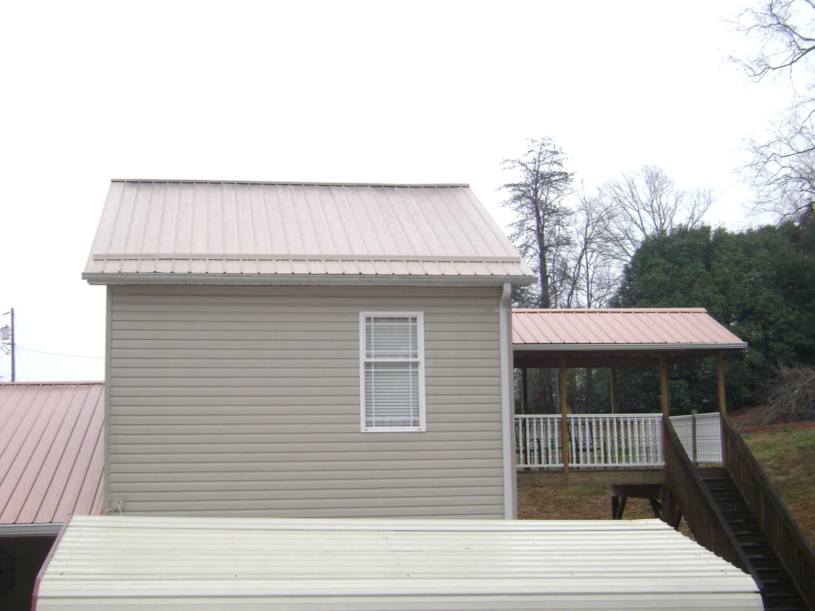 Tan metal roofs on a two story addition and attached porch, from a Roof Replacement job in Plainview